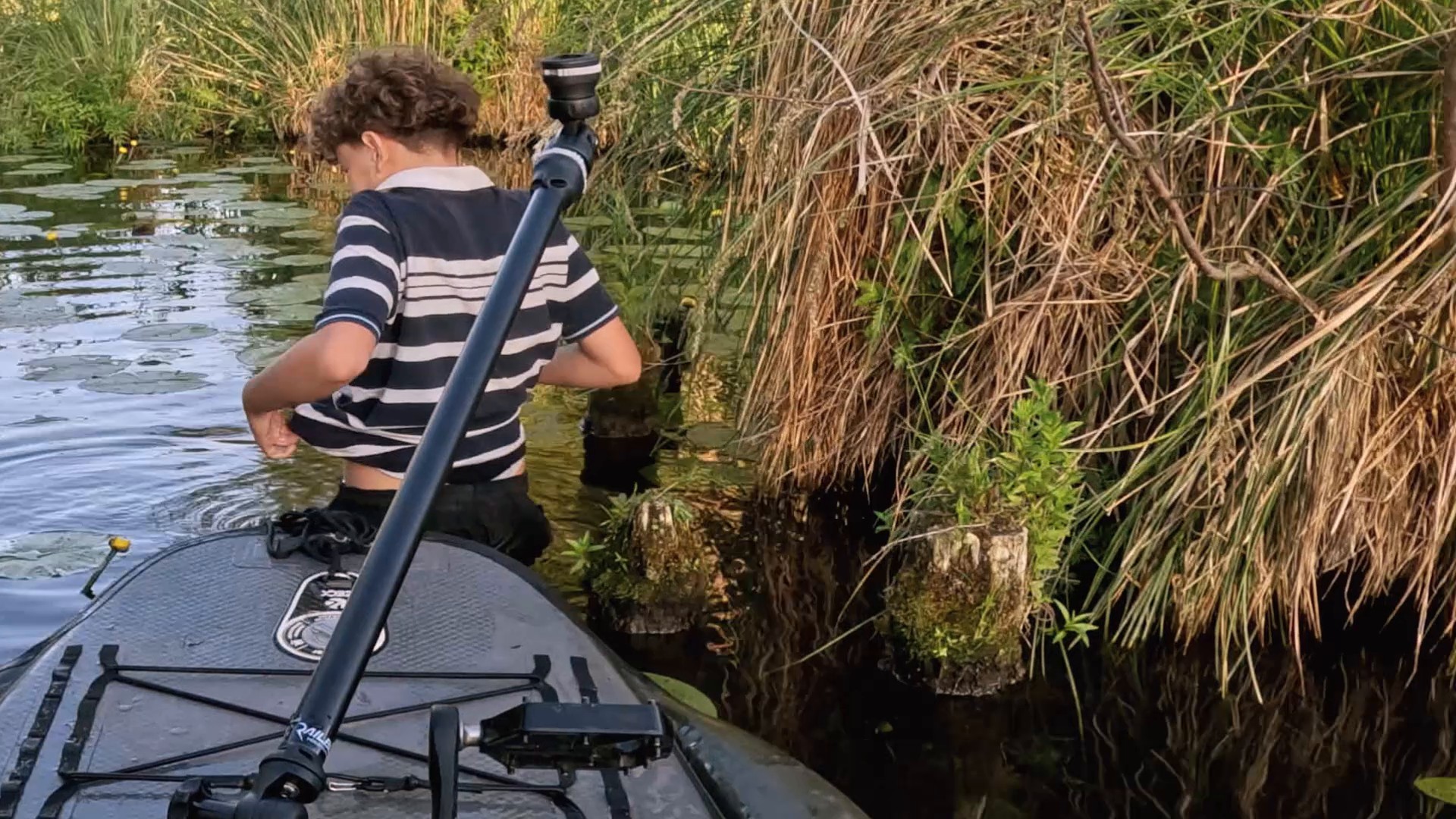 Jakob schiebt das Kajak im Wasser über die Baumstümpfe